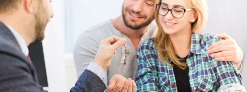 Casal conversa com uma consultora imobiliária durante a procura por um imóvel na Itália.